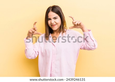 pretty hispanic woman framing or outlining own smile with both hands, looking positive and happy, wellness concept