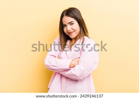 pretty hispanic woman laughing happily with arms crossed, with a relaxed, positive and satisfied pose