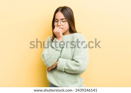 pretty hispanic woman feeling serious, thoughtful and concerned, staring sideways with hand pressed against chin