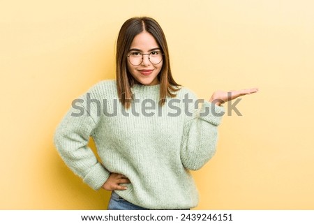 pretty hispanic woman smiling, feeling confident, successful and happy, showing concept or idea on copy space on the side