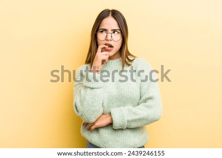 pretty hispanic woman with surprised, nervous, worried or frightened look, looking to the side towards copy space