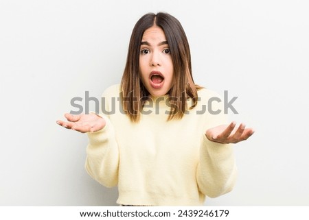 pretty hispanic woman open-mouthed and amazed, shocked and astonished with an unbelievable surprise