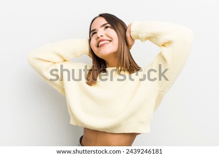 pretty hispanic woman smiling and feeling relaxed, satisfied and carefree, laughing positively and chilling
