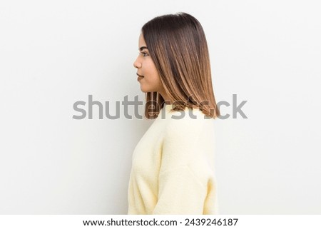 pretty hispanic woman on profile view looking to copy space ahead, thinking, imagining or daydreaming