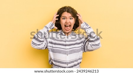 pretty hispanic woman screaming with hands up in the air, feeling furious, frustrated, stressed and upset