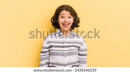 pretty hispanic woman looking happy and pleasantly surprised, excited with a fascinated and shocked expression