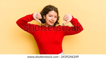 pretty hispanic woman looking sad, disappointed or angry, showing thumbs down in disagreement, feeling frustrated