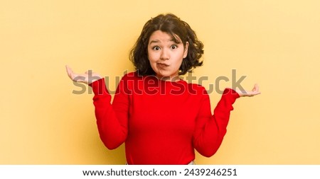 pretty hispanic woman feeling puzzled and confused, doubting, weighting or choosing different options with funny expression