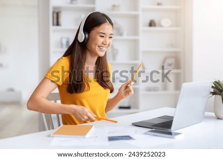 Cheerful Asian Woman Wearing Headphones Having Fun While Using Laptop, joyful Korean Female Listening Music And Pretending Playing Drums, Holding Pens As Drumsticks, Sitting At Desk At Home