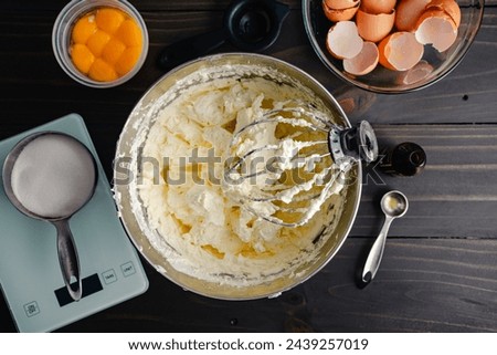 Mixing Bowl Filled with Vanilla Swiss Meringue Buttercream: Wire whisk attachment resting in a bowl of vanilla buttercream frosting or icing Royalty-Free Stock Photo #2439257019