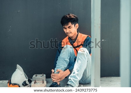 Asian HVAC engineer suffered serious leg injury on the job. Urgent first aid and assistance from coworkers is essential. Expressions of pain on face convey physical and emotional response. Royalty-Free Stock Photo #2439273775