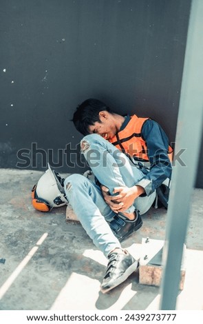 Asian HVAC engineer suffered serious leg injury on the job. Urgent first aid and assistance from coworkers is essential. Expressions of pain on face convey physical and emotional response. Royalty-Free Stock Photo #2439273777