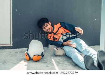 Asian HVAC engineer suffered serious leg injury on the job. Urgent first aid and assistance from coworkers is essential. Expressions of pain on face convey physical and emotional response. Royalty-Free Stock Photo #2439273779
