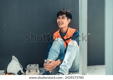 Asian HVAC engineer suffered serious leg injury on the job. Urgent first aid and assistance from coworkers is essential. Expressions of pain on face convey physical and emotional response. Royalty-Free Stock Photo #2439273785