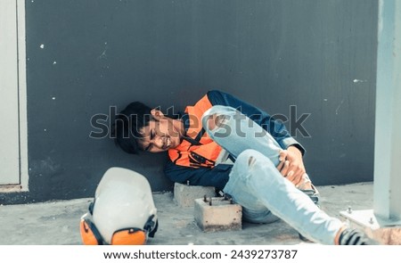 Asian HVAC engineer suffered serious leg injury on the job. Urgent first aid and assistance from coworkers is essential. Expressions of pain on face convey physical and emotional response. Royalty-Free Stock Photo #2439273787