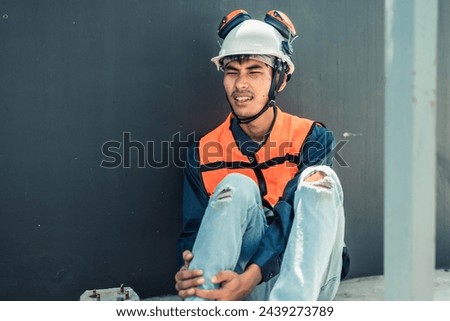 Asian HVAC engineer suffered serious leg injury on the job. Urgent first aid and assistance from coworkers is essential. Expressions of pain on face convey physical and emotional response. Royalty-Free Stock Photo #2439273789