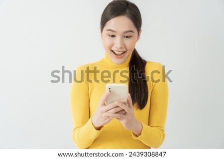 Asian beautiful woman exited surprise face expression . female feels shocked with the phone. exciting smile and happy adorable rejoices. Very enjoy and fun relax time. wow, girl holding smartphone.
