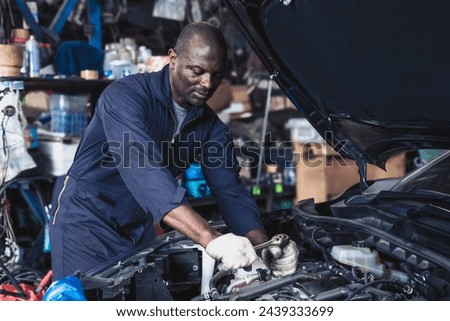 Auto repair man fixing open hood car in repair and maintenance service shop Royalty-Free Stock Photo #2439333699