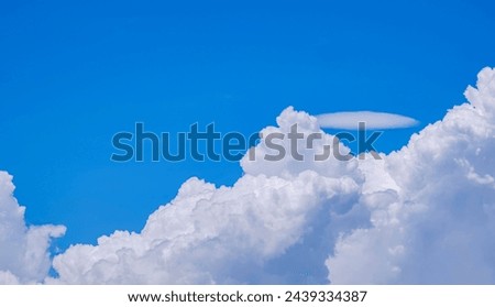 White Cumulus congestus and Pileus clouds on blue sky background in sunny day Royalty-Free Stock Photo #2439334387