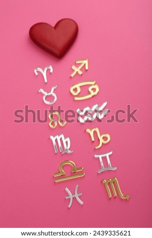 Zodiac compatibility. Signs with red heart on pink background, above view Royalty-Free Stock Photo #2439335621