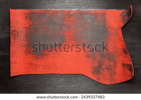 Red leather piece on the black table background with copy space. Top view.