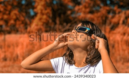 A young girl looking at the sun during a solar eclipse on a country park, family outdoor activity. Royalty-Free Stock Photo #2439340023