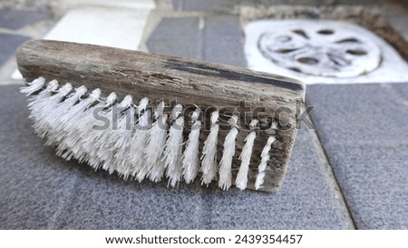 Close up photo of an old wooden brush lying on the floor of the cleaning room. When replacing household appliances.
