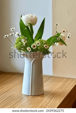 White vase with spring flowers. Spring white daisy and tulips in white vase 
