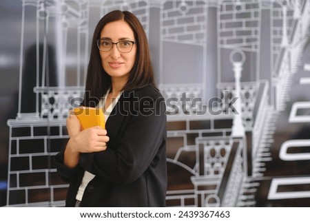 Smiling Business Woman in glasses holds book at office on dark background close up view . 