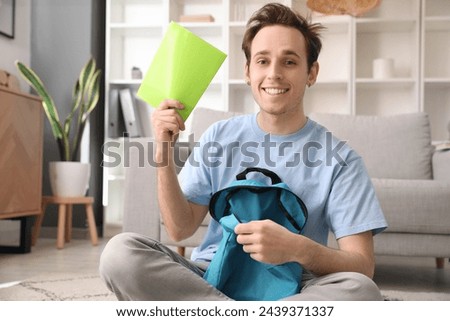 Male student with backpack and notebook at home
