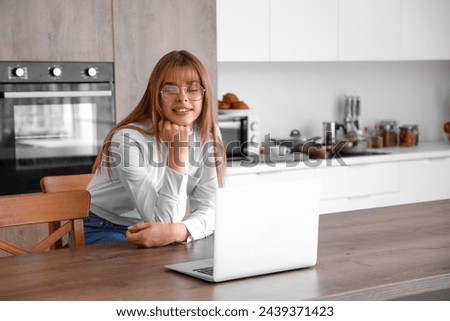 Teenage girl with laptop video chatting in kitchen