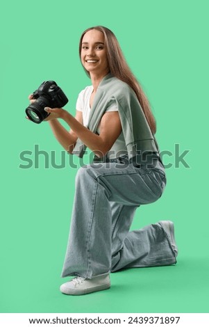 Portrait of female photographer with professional camera on green background