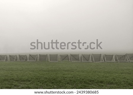Wooden barriers in a fogged landscape, wooden barriers between the road and the field