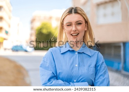 Young pretty blonde woman at outdoors With glasses and happy expression