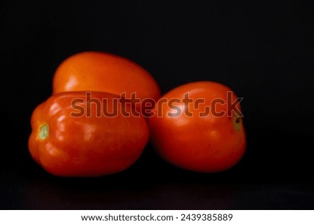 Fresh orange tomatoes in isolated black background
