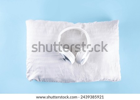 Sonic Hues and Noise for sleep concept with comfortable headphones and white pillow on light blue background top view copy space