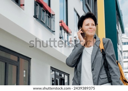 Professional woman talks on her mobile phone while walking in the city, displaying a blend of business and urban life.