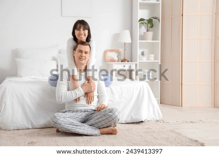 Young woman hugging her husband in bedroom