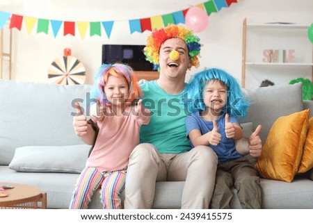 Father and his children with colorful wigs showing thumbs-up at home. April Fool's Day celebration Royalty-Free Stock Photo #2439415575