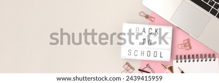 Banner with quote Back to school. Workspace with laptop and office supplies on a gray and pink background. 