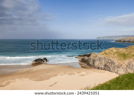 The unspoiled charm of Durness Beach, Scotland, is evident in the gentle embrace of azure waters against the pristine sandy shore Royalty-Free Stock Photo #2439421051