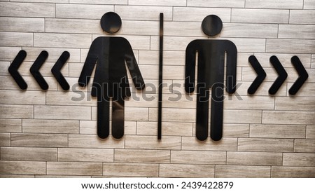 Male and Female Restroom Symbols on Wooden Wall With Directional Arrows. Gender-specific bathroom signs on wood surface