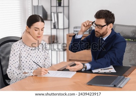 Injured woman signing document in lawyer's office