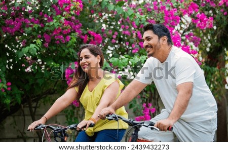 Indian young Couple on bikes or bicycle outdoors smiling