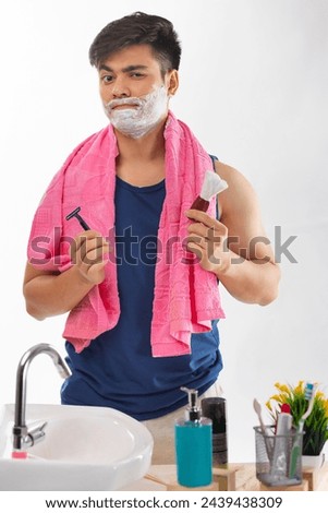 Portrait of young boy looking himself in mirror while shaving in bathroom