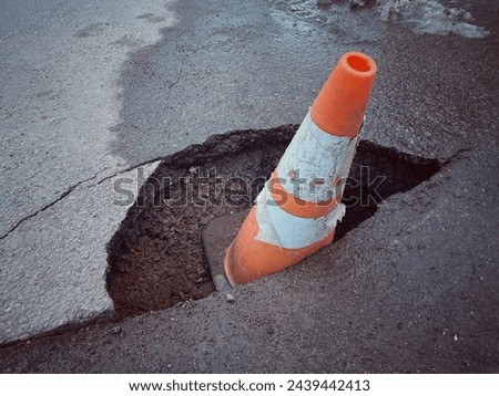 Traffic cone and hole in the road.