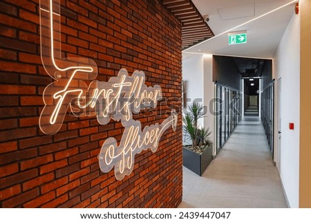 Long corridor with a brick wall and a neon sign