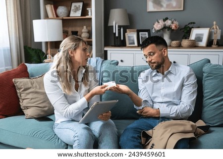 Man and woman home finances argue with credit card and digital tablet, online shopping and spending money. Relationship difficulties of married couple and bank account they have together Royalty-Free Stock Photo #2439459601