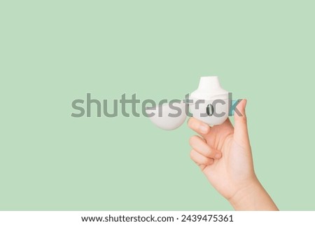 Asthma and COPD concept. Female hand holding Tiotropium bromide  inhaler on green background. Pharmaceutical device of bronchodilator for lung inflammation treatment and prevent asthma attack. Royalty-Free Stock Photo #2439475361