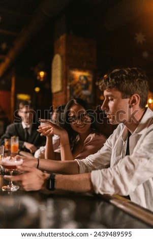 Young couple spends romantic time in trendy restaurant with muffled light. People in love have fun together on date in trendy place Royalty-Free Stock Photo #2439489595